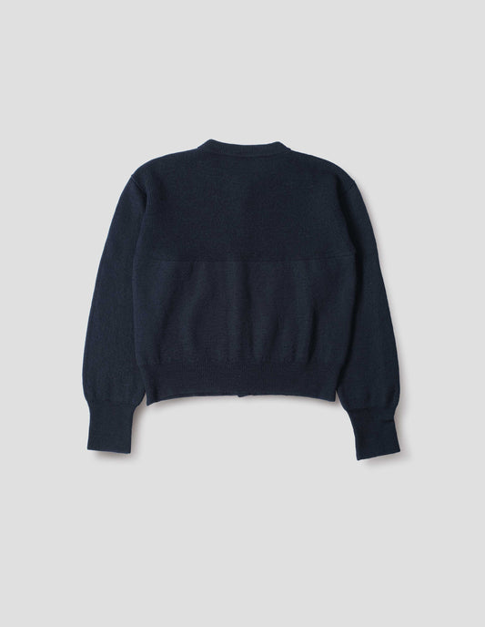 Dark navy blue wool textured cardigan, with contrast panel across upper back and rib detailing on neck, cuffs and hem. Back flat lay view. 