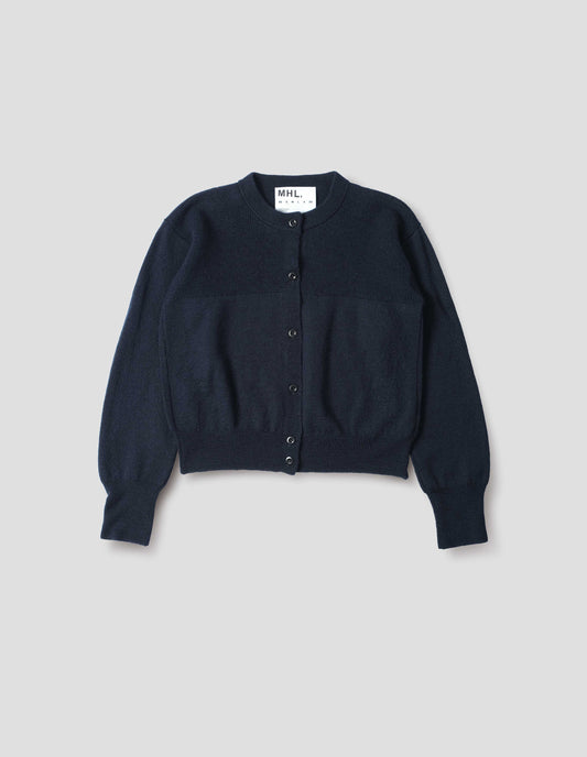 Dark navy blue wool textured cardigan, with contrast panel across chest, rib detailing on neck, cuffs and hem and corozo button closure. Front flat lay view. 