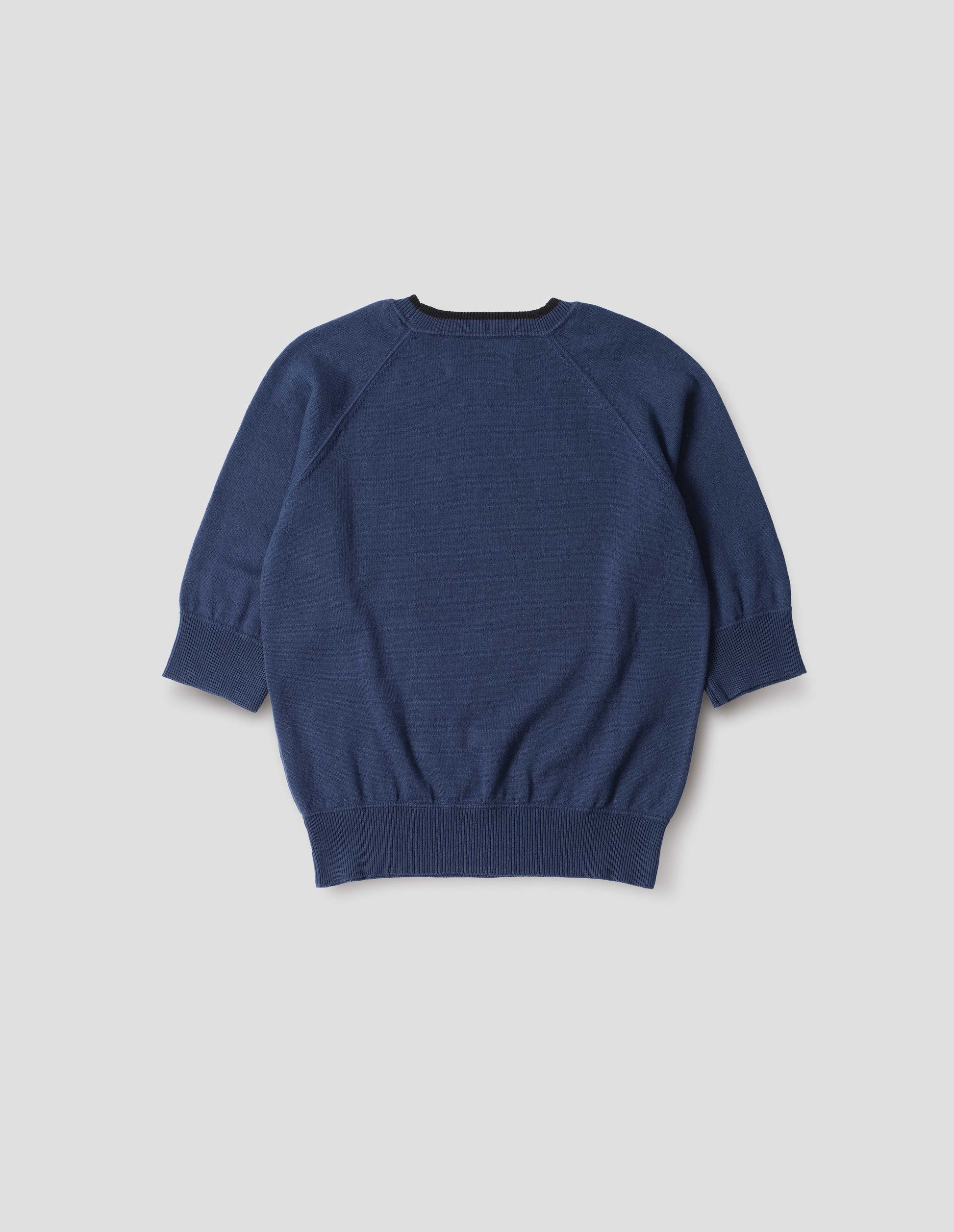 Blue short sleeve knitted t-shirt, with contrast black stitching on neckline, raglan sleeve, flatlock stitch seam detailing and contrast rib on sleeve and hem. Back flat lay view.