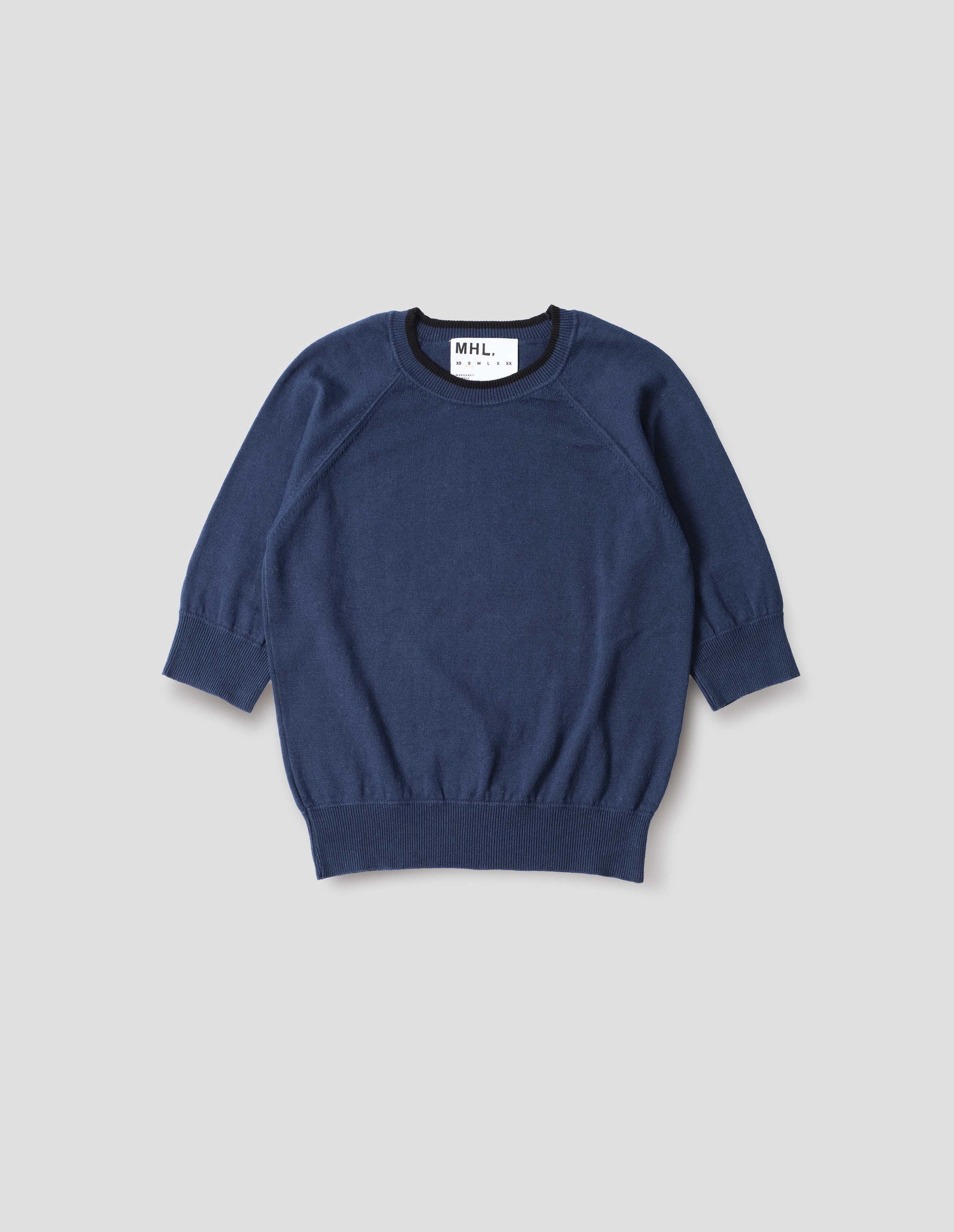 Blue short sleeve knitted t-shirt, with contrast black stitching on neckline, raglan sleeve, flatlock stitch seam detailing and contrast rib on sleeve and hem. Front flat lay view.
