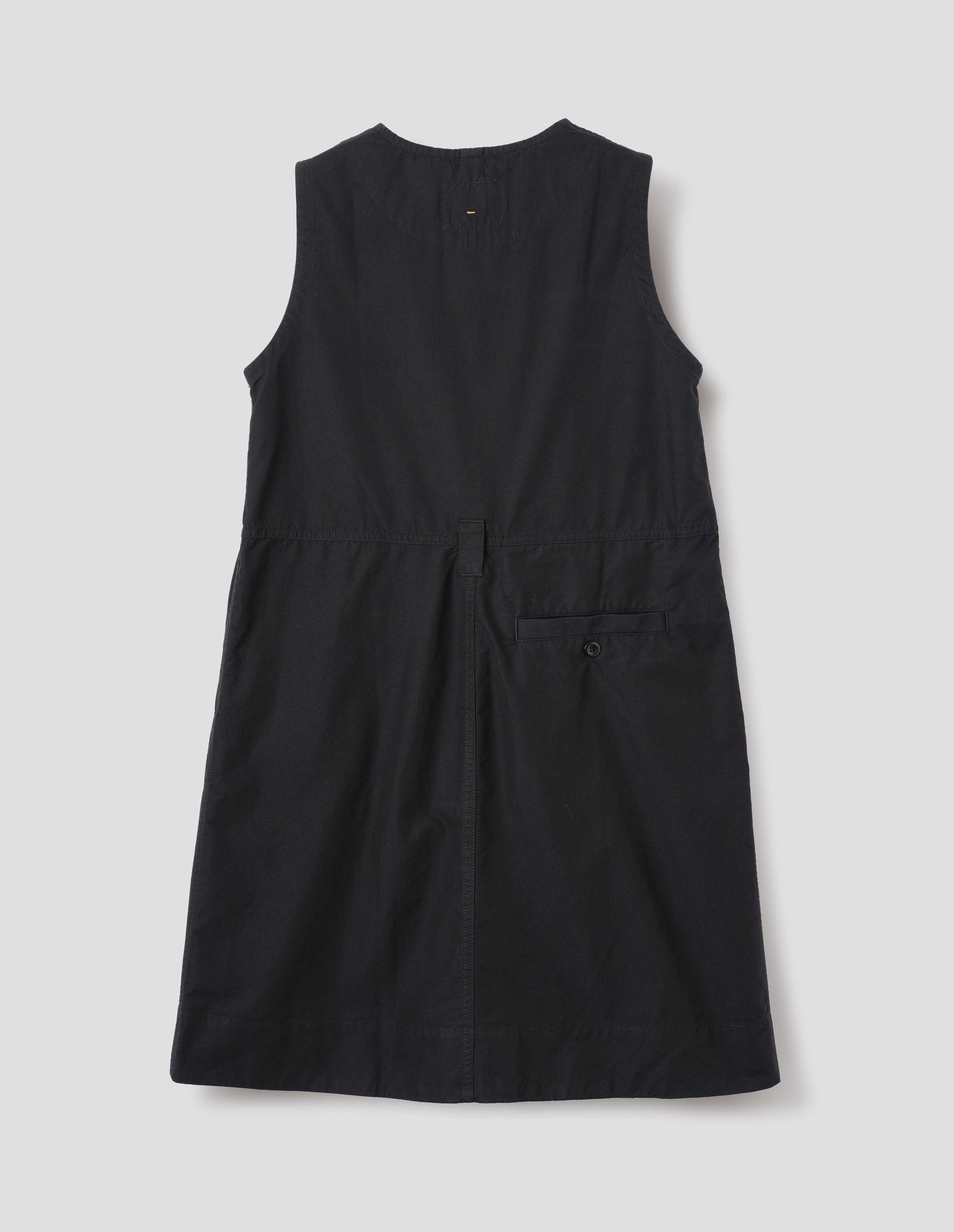 Black sleeveless dress with singular belt loop and back button through welt pocket. Back flat lay view. 