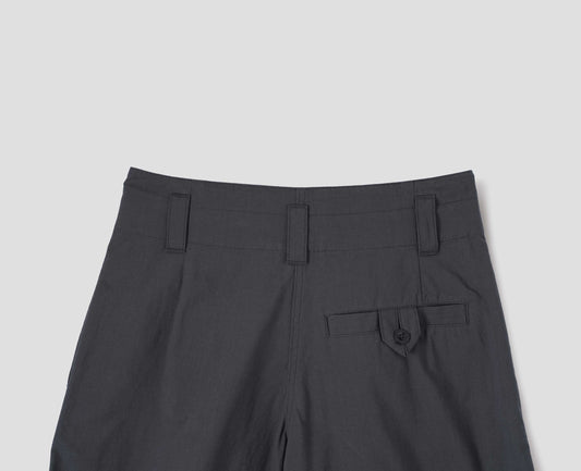 Grey culottes with stitch-through waistband and dropped belt loops, and corozo button loop fastening welt pocket. Back flat lay view.