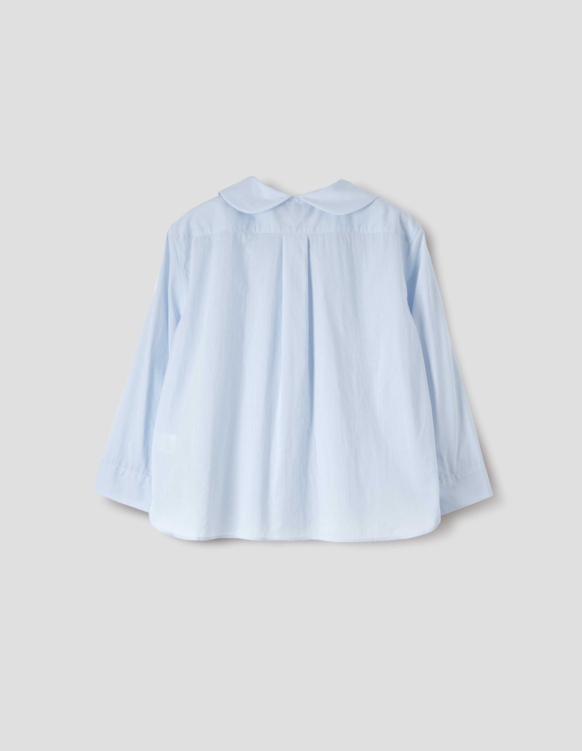 Light blue cotton shirt, with round petal collar, box pleats on back yoke, three quarter sleeves with turned back cuff detail. Back flat lay view.
