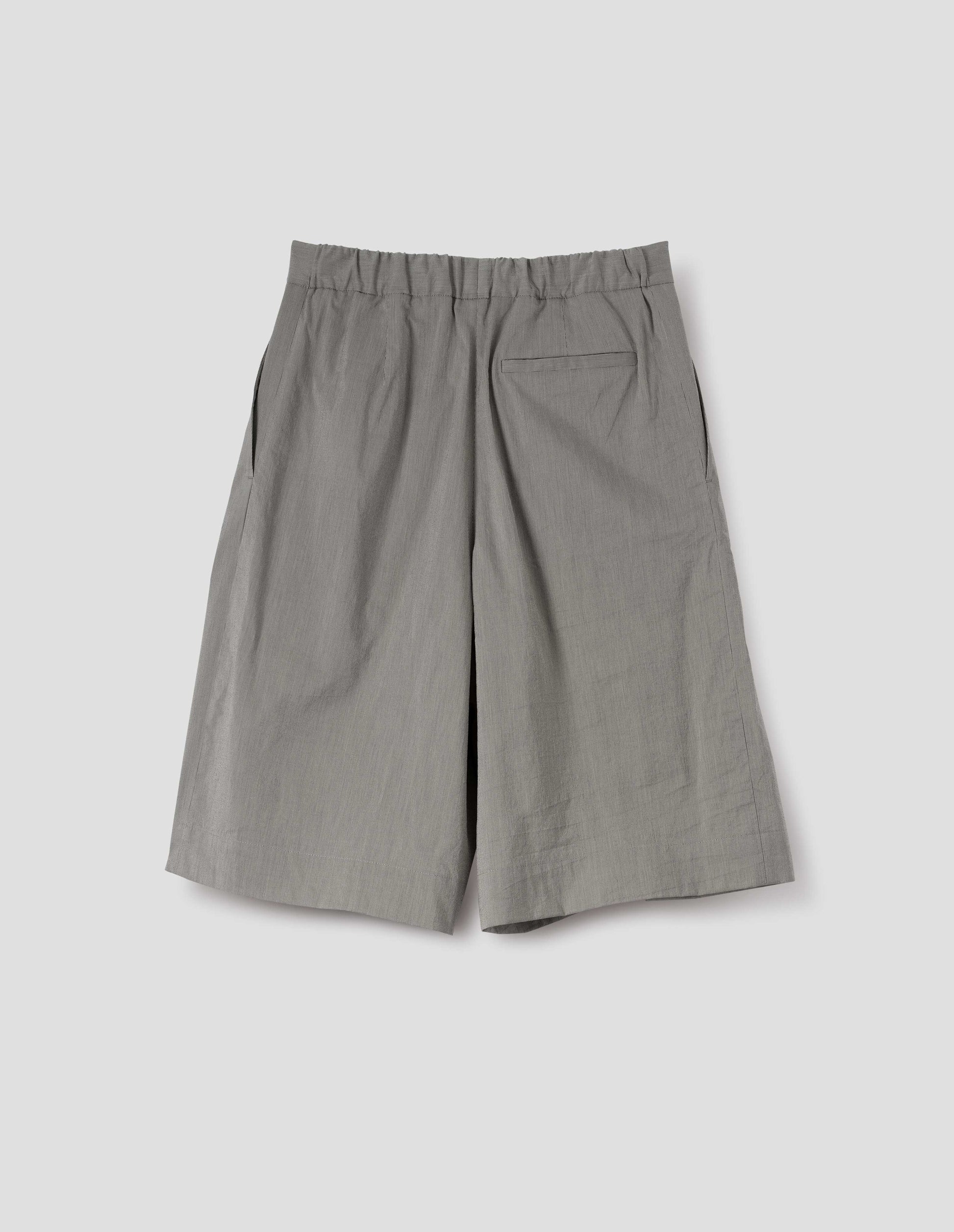 Black and cream stripe long shorts with half-elasticated waist, slant side pockets and welt back pocket. Back flat lay view.