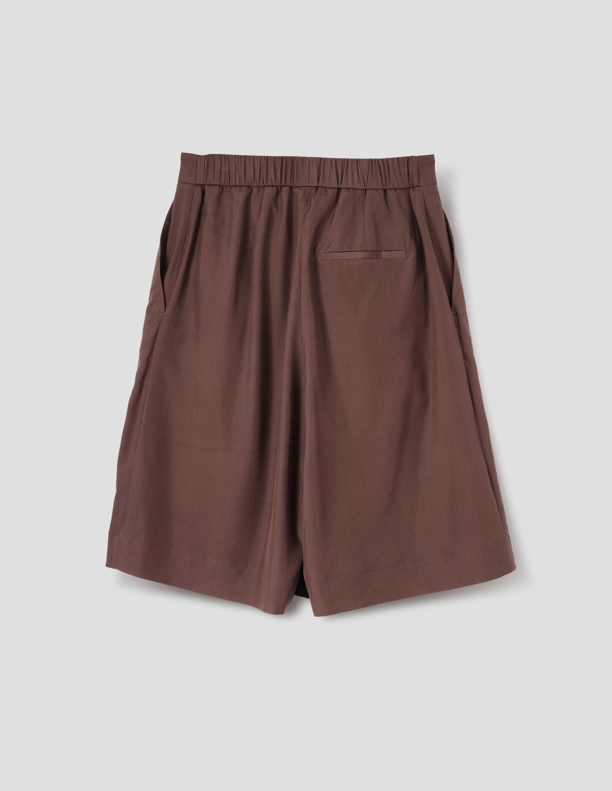 Brown long shorts with half-elasticated waist, slant side pockets and welt back pocket. Back flat lay view.