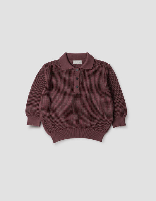 Brownish red cotton cashmere pointelle polo shirt, with solid seam detailing, rib collar, placket, cuffs and hem and horn button closure. Front flat lay view.