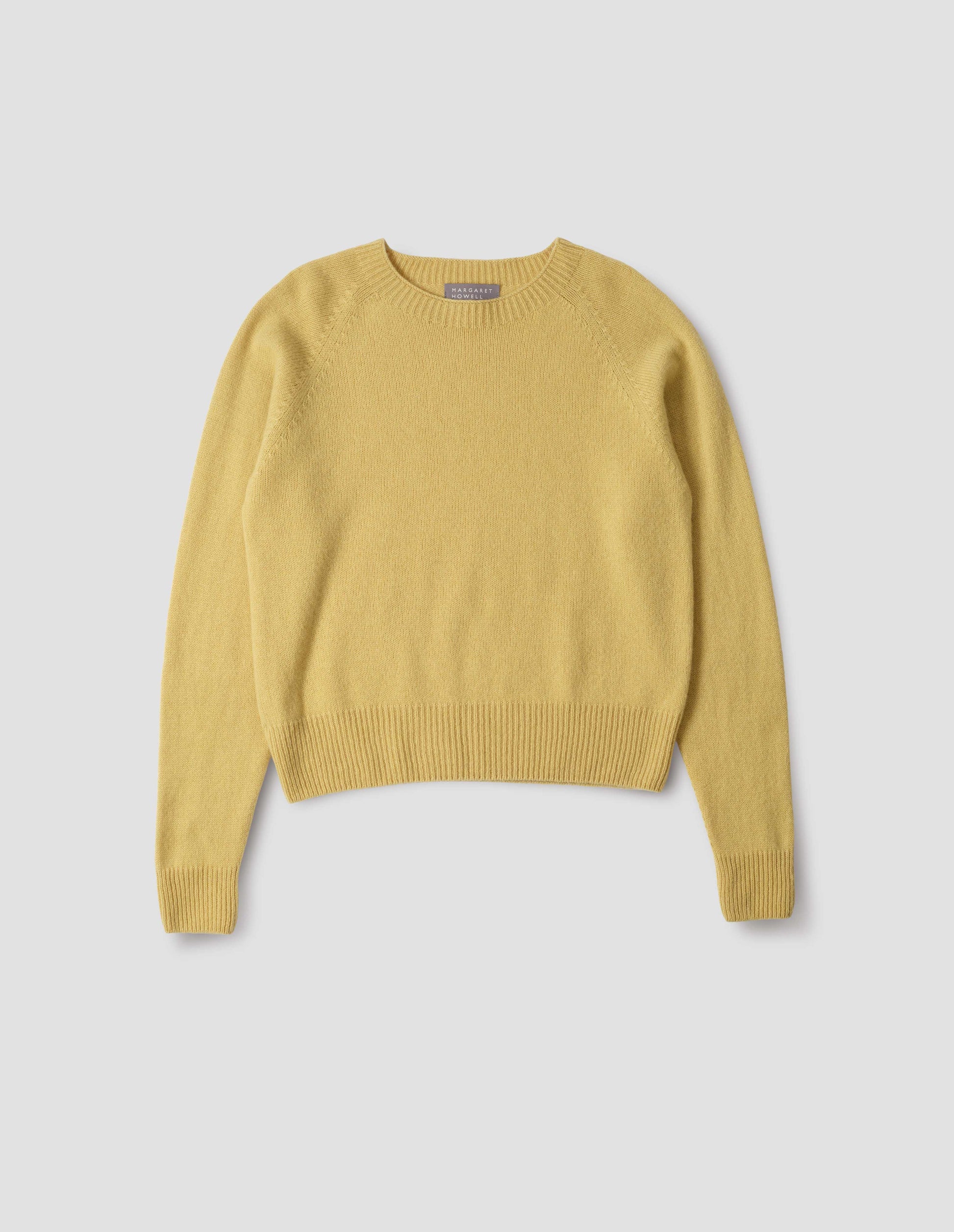 Yellow merino cashmere long sleeve jumper, with raglan sleeve and contrast rib on neck, cuffs and hem. Front flat lay view.
