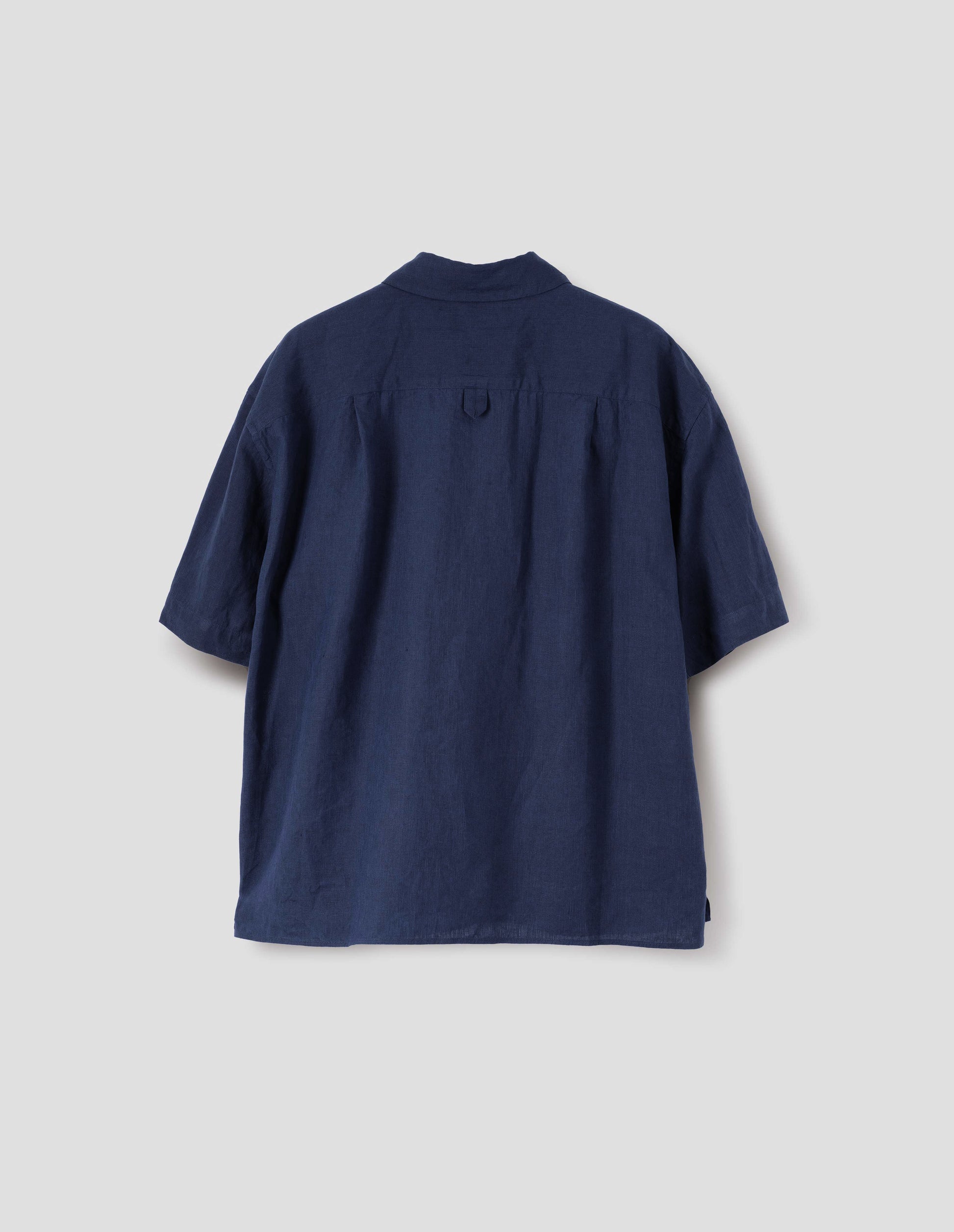 Dark blue linen short sleeve shirt, with dropped shoulder, side split hem and hanger loop on back yoke. Back flat lay view.