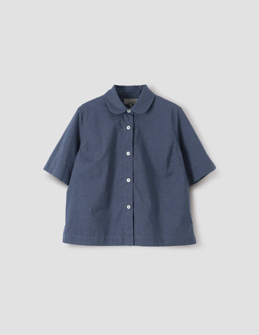 Light blue cotton short sleeve shirt, with rounded collar, mother of pearl buttons and side split hem. Front flat lay view.