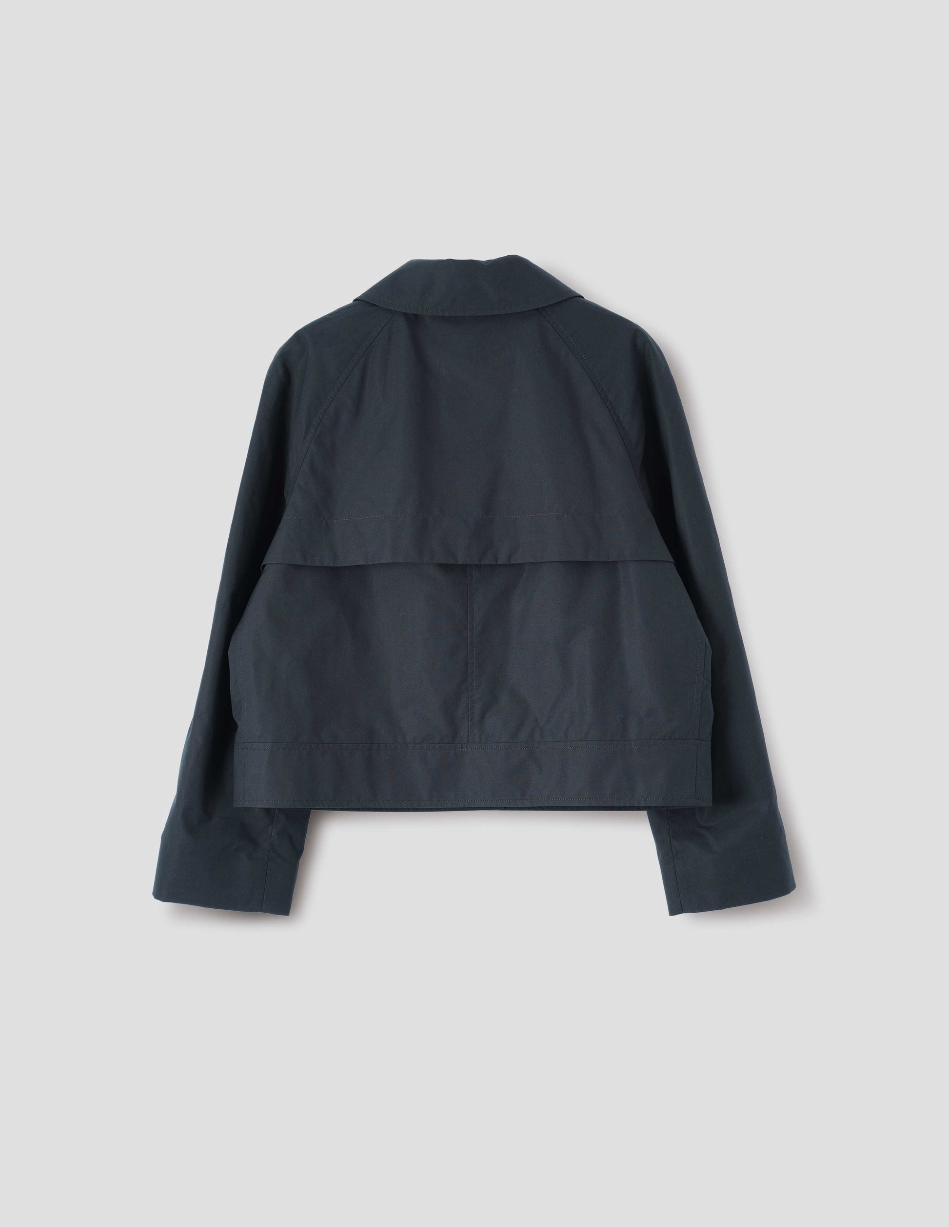Black ventile cotton poplin long sleeve short trench, with storm vent. Back flat lay view.