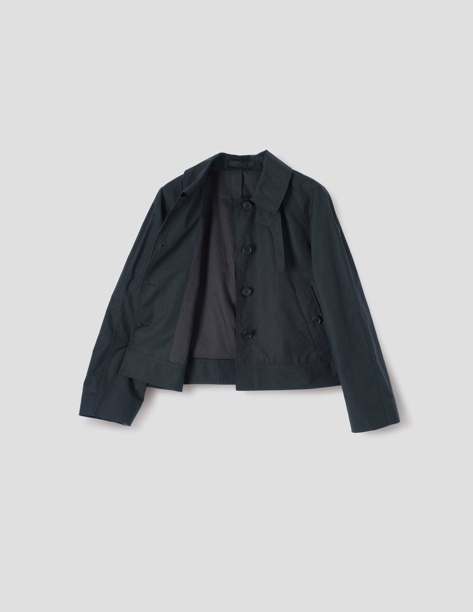 Black ventile cotton poplin long sleeve short trench, with horn button closure, slant side pockets, adjustable storm tab, black lining and hanger loop on collar, front flat lay open view. 