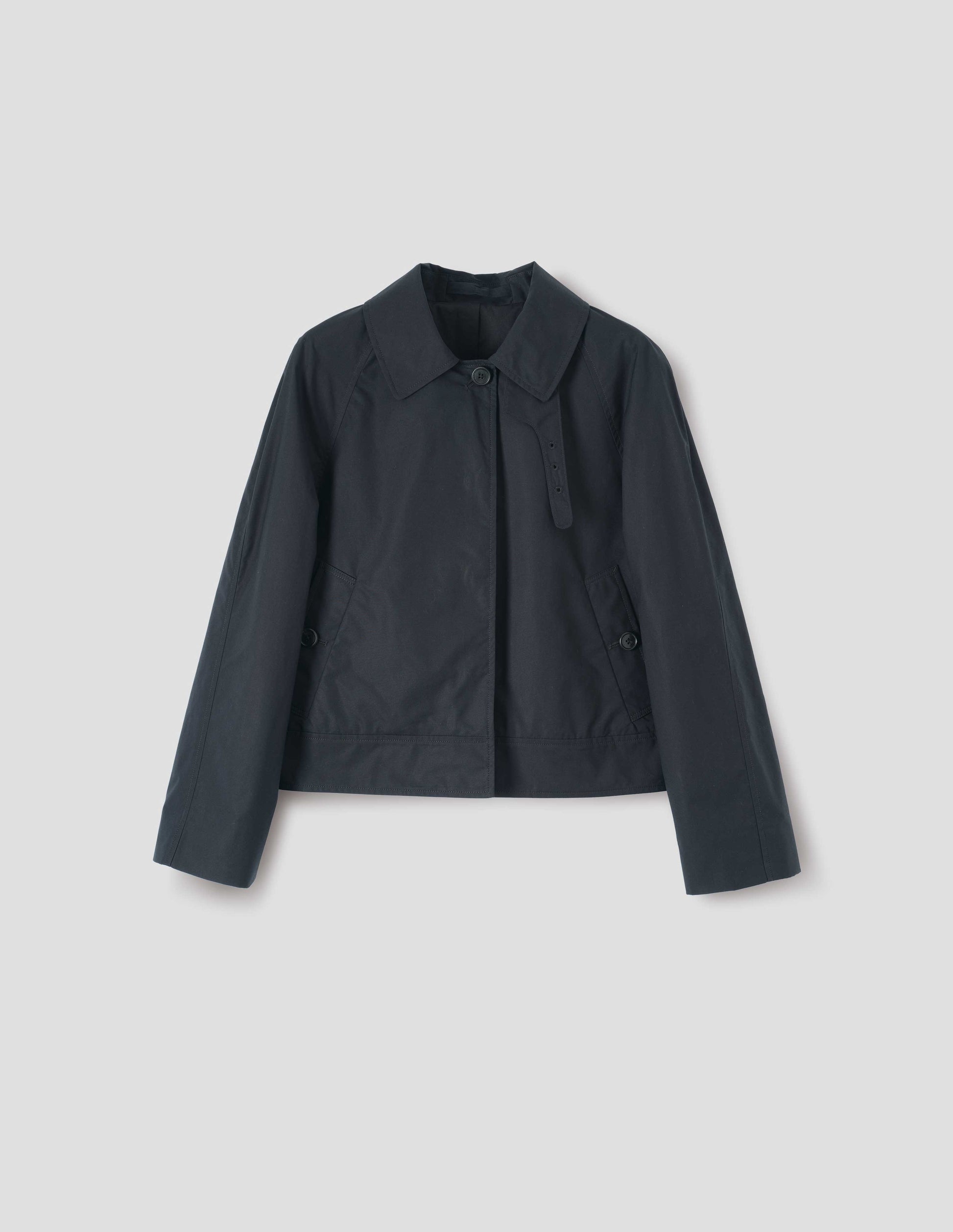 Black ventile cotton poplin long sleeve short trench, with horn button closure, slant side pockets, adjustable storm tab and hanger loop on collar, front flat lay view. 