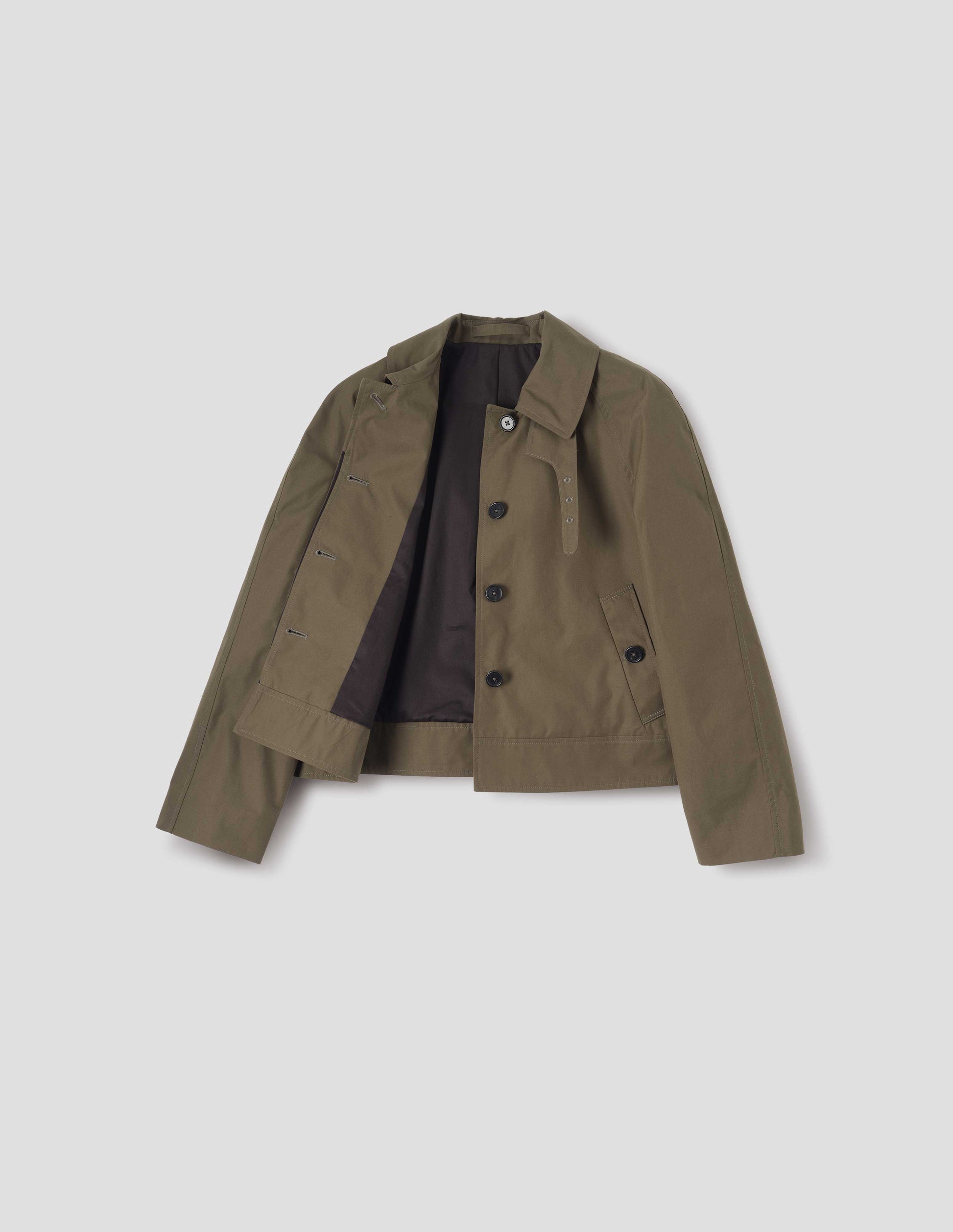 Greenish brown ventile cotton poplin long sleeve short trench, with horn button closure, slant side pockets, with removable storm tab, hanger loop on collar and contrast black lining, front flat lay open view. 
