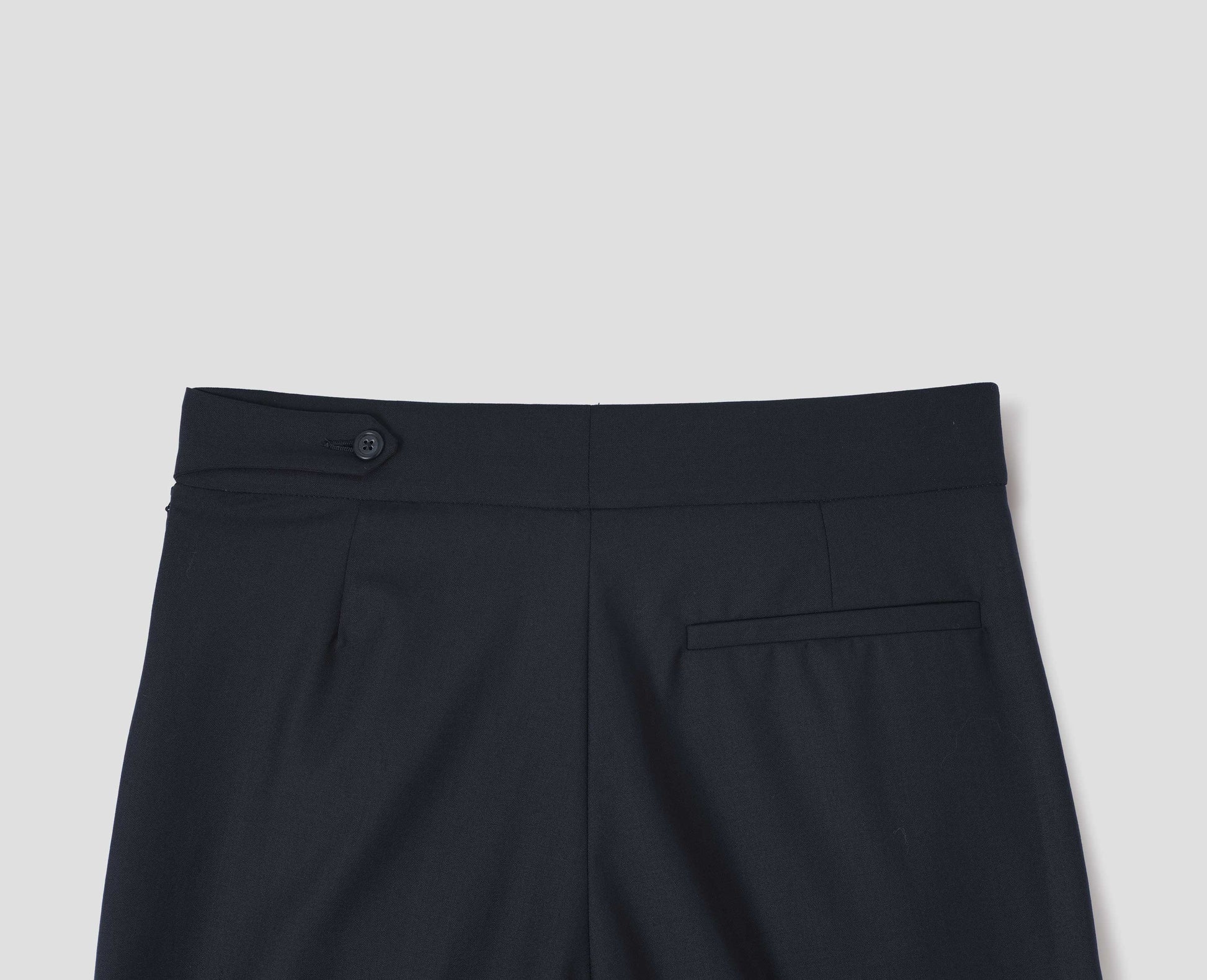 Dark navy summer wool trousers with pull through double tab side fastening and back pocket, back flat lay view.