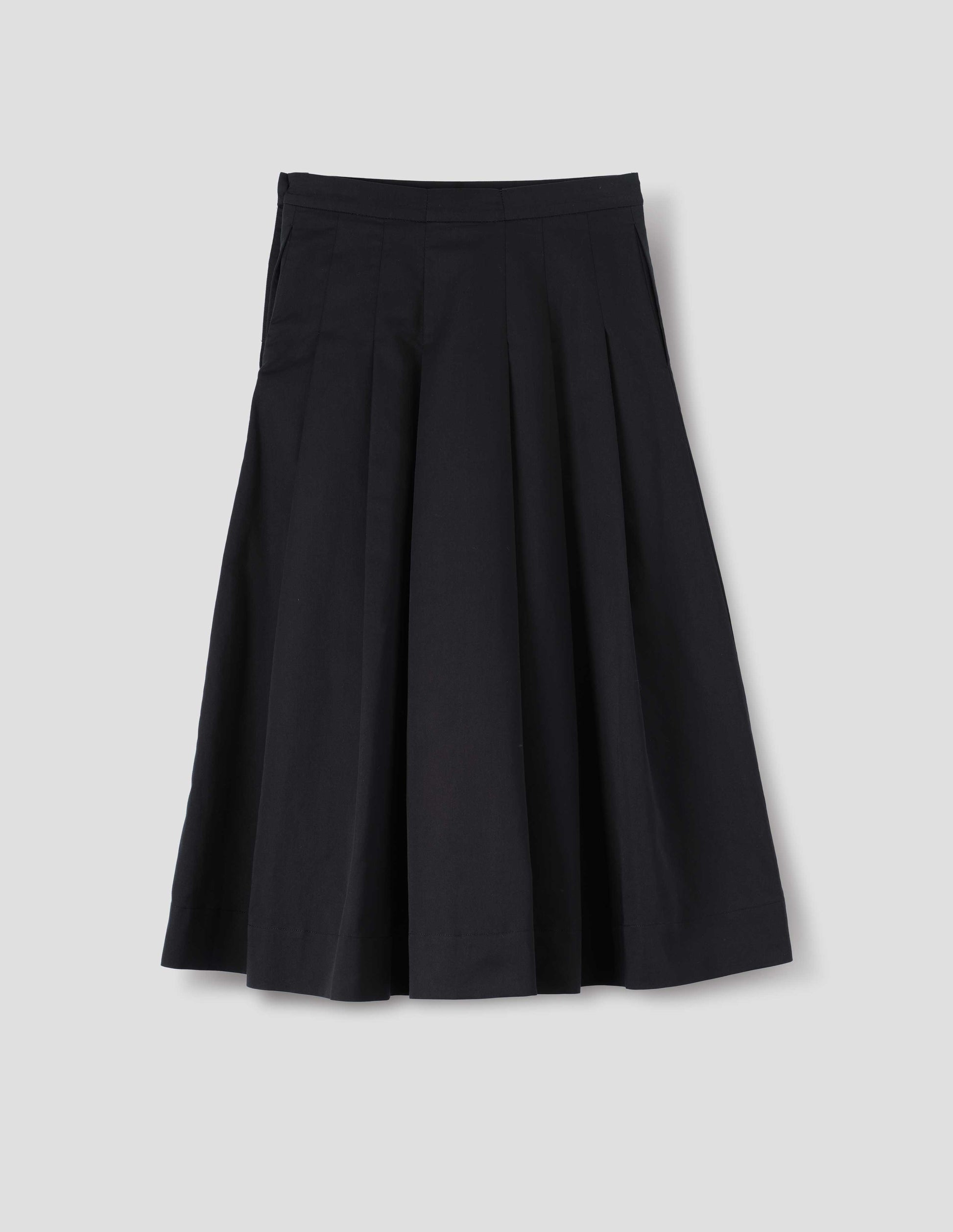 Black relaxed cut below knee skirt, minimal waistband, stitched down pleats, and concealed side seam pockets. Back flat lay view. 