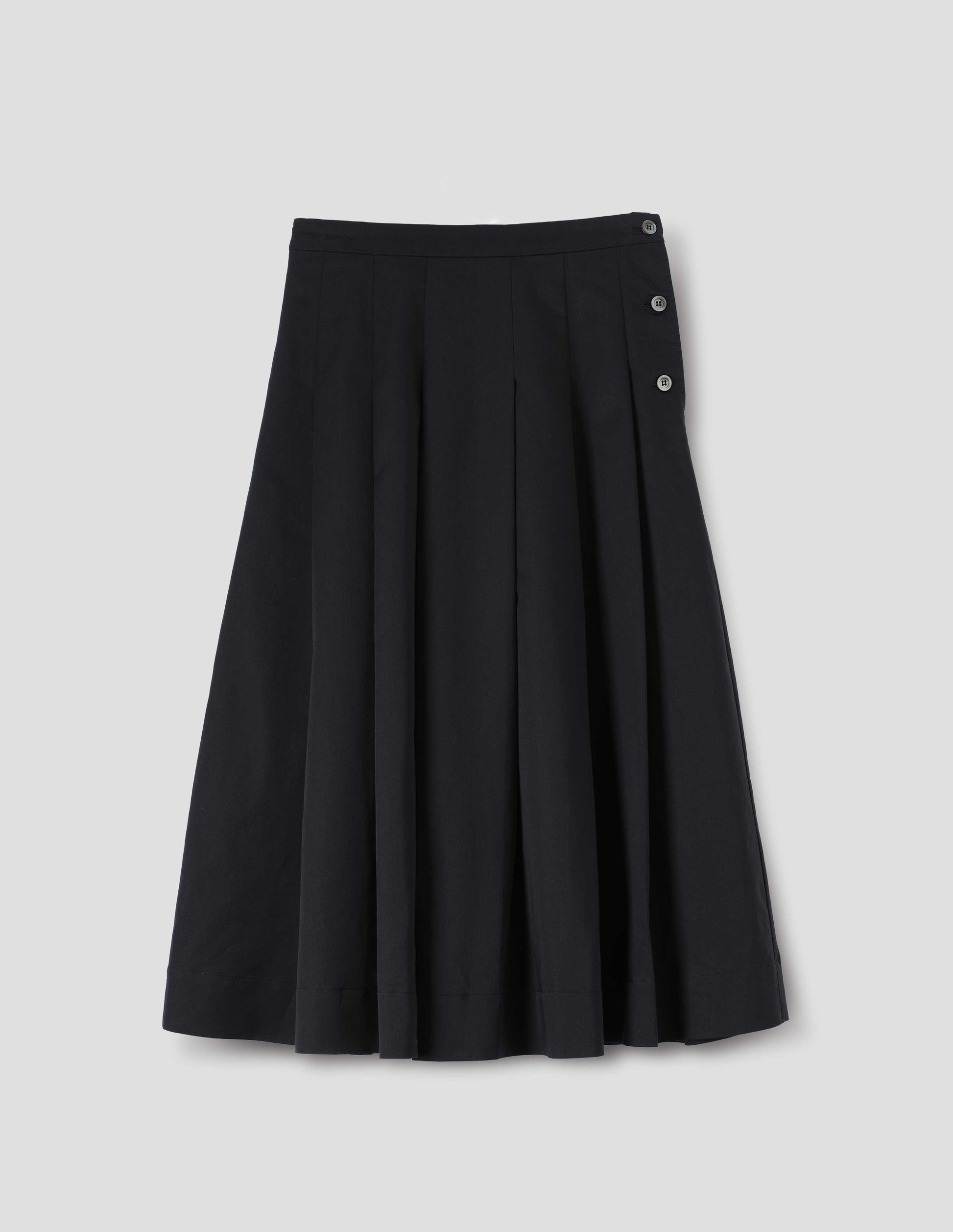 Black  relaxed cut below knee skirt, minimal waistband and side button fastening, stitched down pleats, and concealed side seam pockets. Front flat lay view.