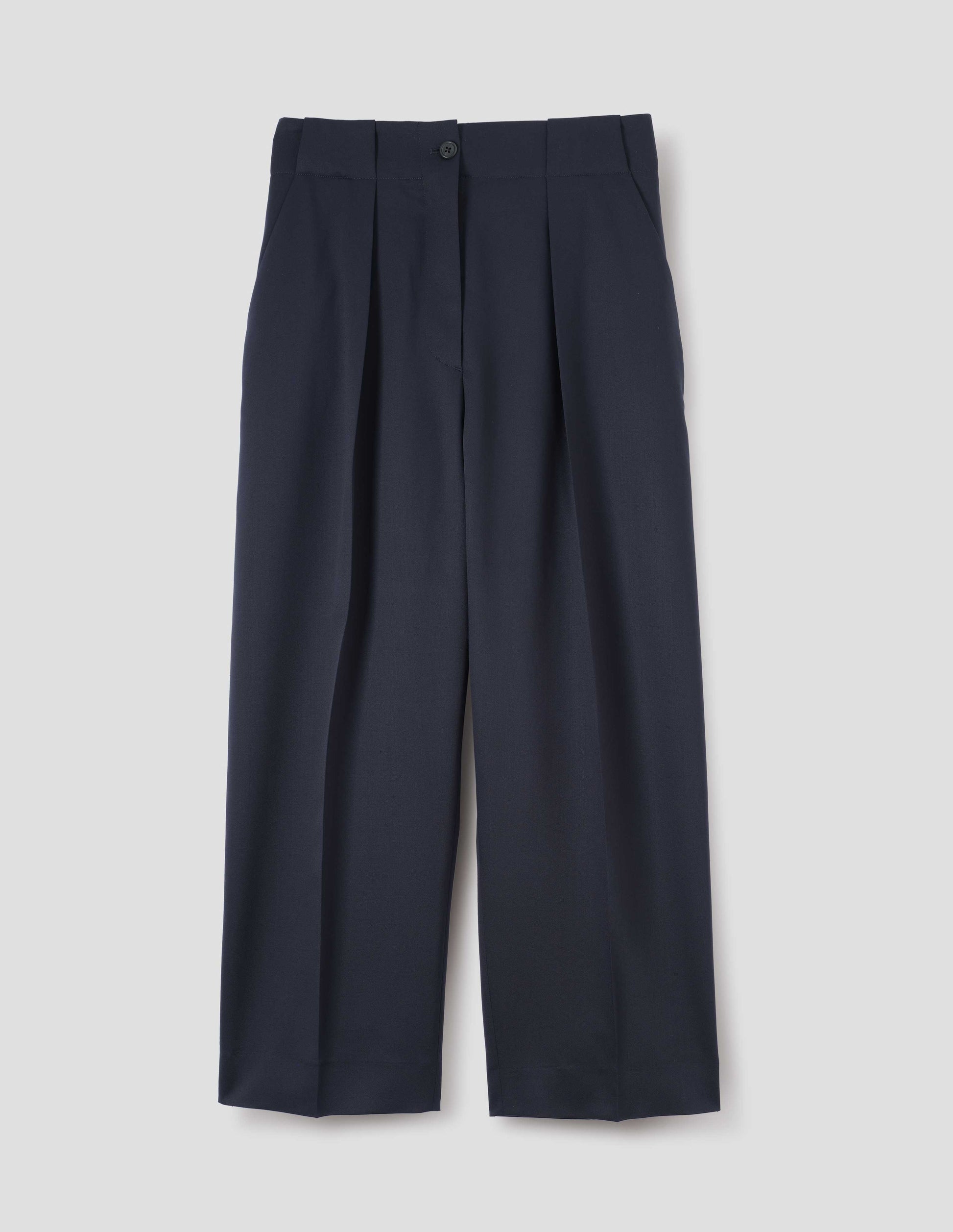 Dark navy wool trousers, single pleats and grown-on waistband with large belt loops and horn button. Front flat lay view.