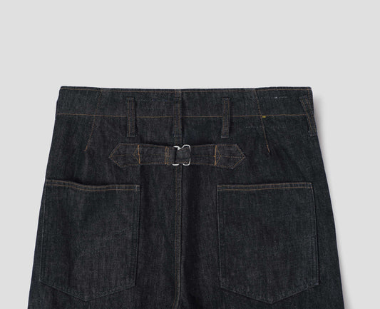 Black denim twill jeans, with stitch-through waistband with belt loops, cinch back detail with metal buckle and patch back pockets. Back flat lay view.