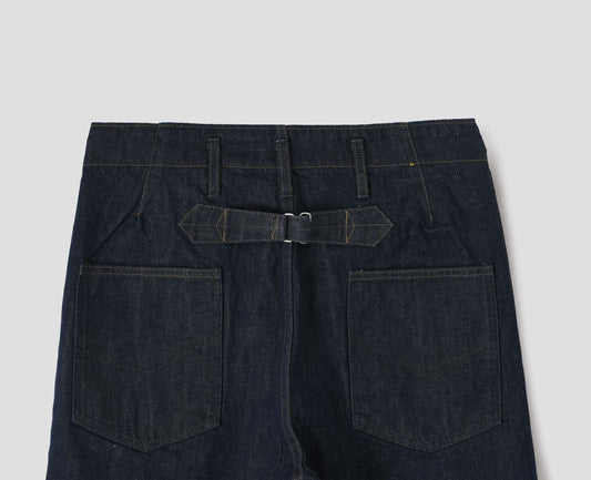 Indigo blue denim twill jeans, with stitch-through waistband with belt loops, cinch back detail with metal buckle and patch back pockets. Back flat lay view.