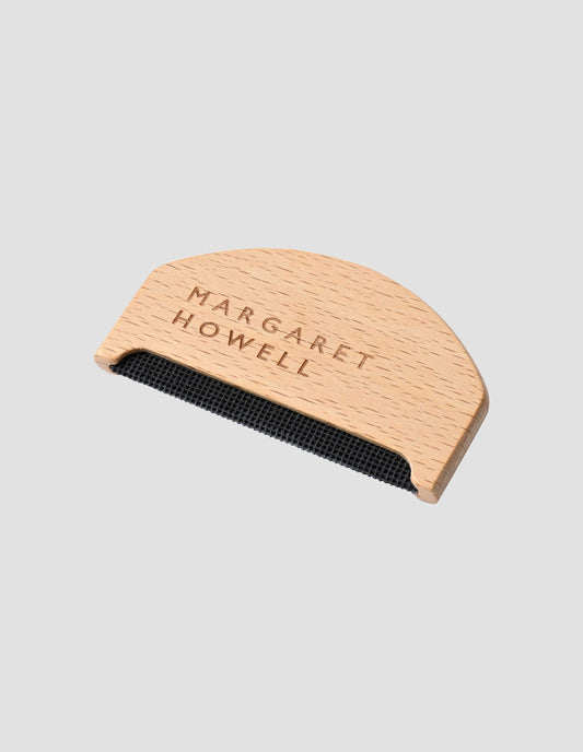 Wooden unvarnished knitwear comb with Margaret Howell logo. Side flat lay view.