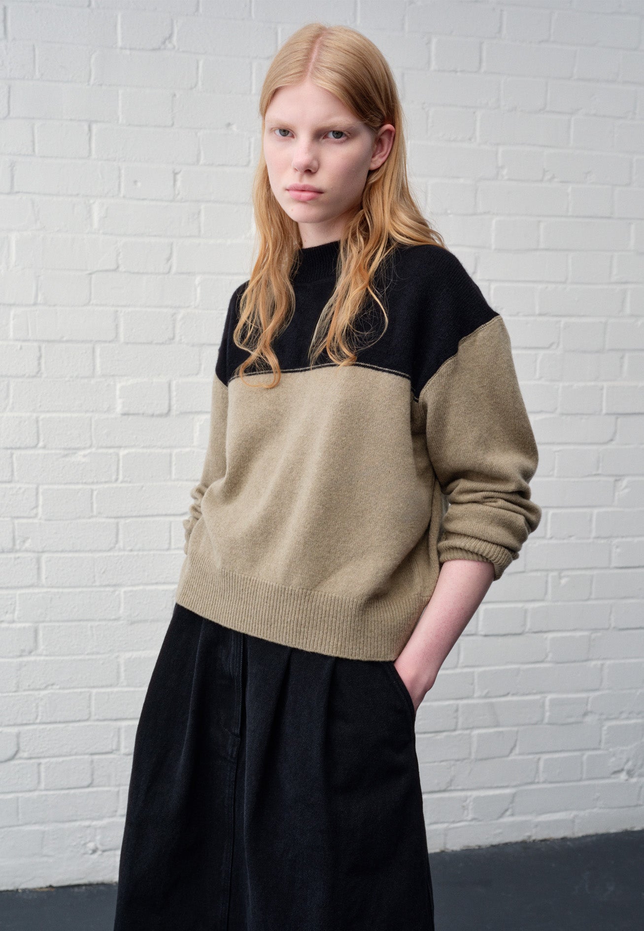 Cropped image, front view of model wearing cropped black and beige jumper with ribbed crew neck, cuffs and hem. Styled with black skirt.