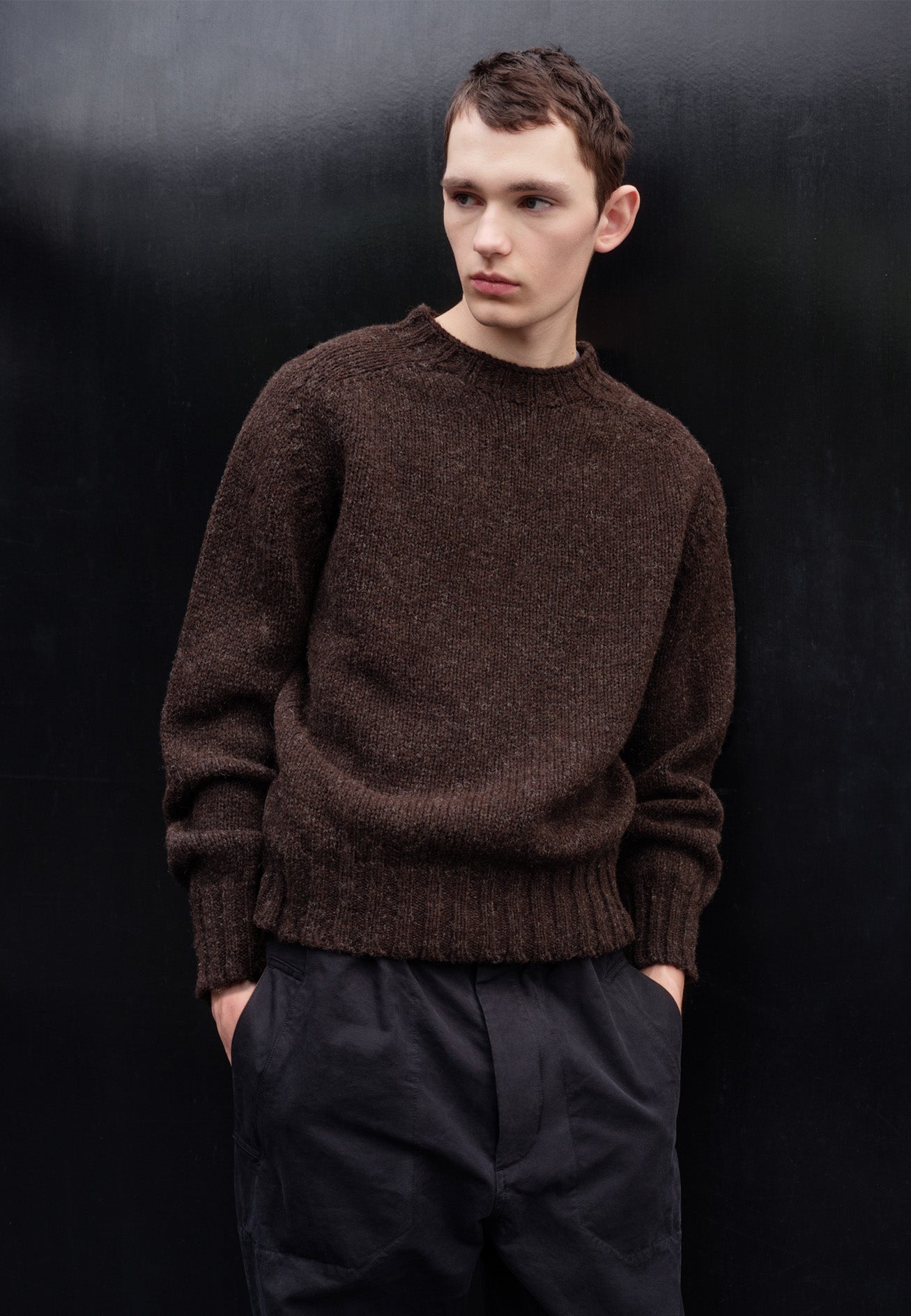 Cropped body image, front view of model wearing dark brown marl jumper with saddle sleeves and contrasting rib on neck, cuffs and hem. Styled with navy blue trousers.